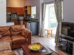 ein Wohnzimmer mit Couch und Küche in der Unterkunft Orchard Cottage in Pwllheli