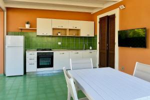 a kitchen with a table and a white refrigerator at Le terrazze house with swimming pool in Terrasini in Terrasini
