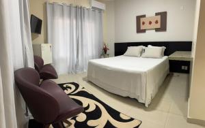 a bedroom with a white bed and a chair at Hotel Yoguedes in Padre Paraíso