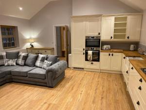 a living room with a couch and a kitchen at Pointer Cottage in Preesall