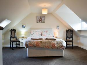a bedroom with a bed and two chairs at Cygnet Cottage - Uk43546 in Belford +7 photos