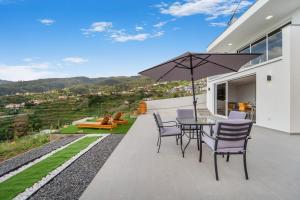 カリェタにあるBrand new private modern apartment with Patio and Sea Viewのテーブルと椅子と傘のあるパティオ