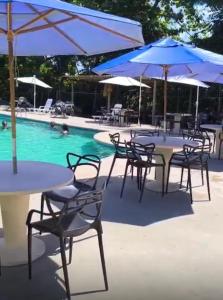 a group of tables and umbrellas next to a pool at Boulevard da Praia Apart Hotel - Porto Seguro - Frente da Praia de Taperapuan in Porto Seguro