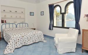 um quarto com uma cama, uma cadeira e uma janela em La Casetta di Marmorata - Ravello Accommodation em Ravello