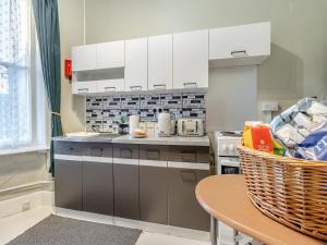a kitchen with white cabinets and a table at The Flat in Whitchurch