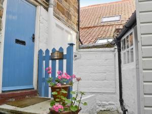 a house with a blue door and some flowers at Sharrowhead Cottage - E4044 in Robin Hood's Bay +2 photos
