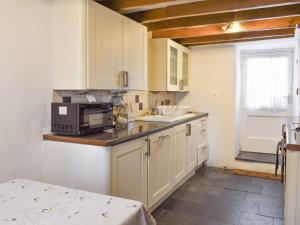 a kitchen with white cabinets and a microwave at Tryfar House in Harlech