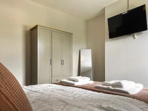 a bedroom with a bed with a tv on the wall at Alders Cottage in Tansley +7 photos