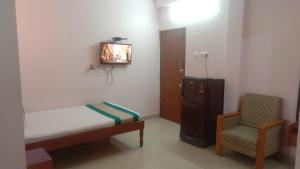 a small bedroom with a bed and a chair at Five Stones By Terra Hotel Mogappair in Chennai