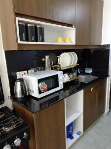 a kitchen counter with a microwave and dishes on it at Home Away in Ongata Rongai  +4 photos