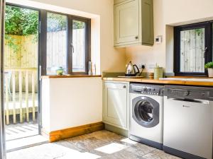 a kitchen with a washer and dryer next to a window at Wood-Side Cottage in Backbarrow