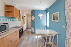 ヴァーレンにあるBlaue Kombüse Altstadt Ferienwohnung im Fischerhausの青い壁のキッチン(テーブル、椅子付)