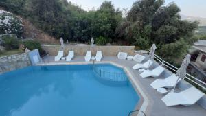 a large swimming pool with white chairs and a swimming pool at Ponti Beach Hotel in Vasiliki