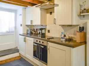 a kitchen with white cabinets and a stove top oven at Tryfar House in Harlech