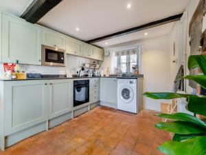 eine Küche mit weißen Schränken und einer Waschmaschine und einem Trockner in der Unterkunft Cherry Tree Cottage - Uk30237 in Great Snoring