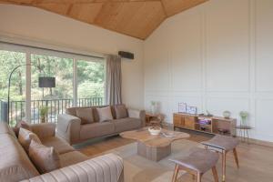 un salon avec un canapé et une table dans l'établissement StayVista at Glass Forest with Bonfire, BBQ, à Mussoorie