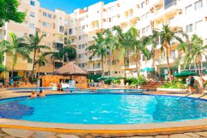 a swimming pool in a resort with palm trees and buildings at Thermas Paradise - Duplex in Rio Quente