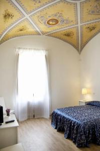 1 dormitorio con techo, cama y ventana en Relais La Corte dei Cavalieri, en Siena
