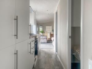 a kitchen with white cabinets and a hallway at Meadows Farm Lodge - Uk47614 in Gorseinon +13 photos