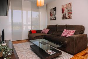 uma sala de estar com um sofá castanho e uma mesa de vidro em Tranquilidad con vistas de Vigo by CABANA Rentals em Vigo