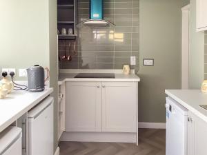 une cuisine avec des armoires blanches et un évier dans l'établissement Covina - Uk43994, à Anderby 13 autres photos