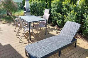 a table and chairs on a deck with a table and a bench at Sea Suite Garden & Pines in Łukęcin