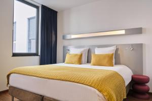 a bedroom with a large bed with yellow pillows at Hotel Aqua by HappyCulture in Brussels +18 photos
