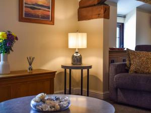 un salon avec une table, une chaise et une lampe dans l'établissement The Studio At Malt Kiln Cottage, à Grizebeck