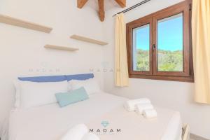 une chambre blanche avec un lit et une fenêtre dans l'établissement White Cottage, à Olbia