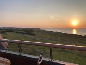 a view of the ocean at sunset from a balcony at Penthouse Golf View Apartments in Lossiemouth