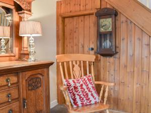 een houten stoel met een kussen erop naast een klok bij Beck Foot Cottage in Sedbergh