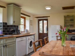 een keuken met een tafel met een vaas met bloemen bij Beck Foot Cottage in Sedbergh +10 foto's