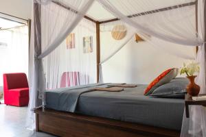 a bedroom with a canopy bed with a red chair at SriMany in Mirissa