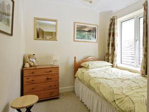 a bedroom with a bed and a dresser and a window at Bridge Cottage in Braithwaite