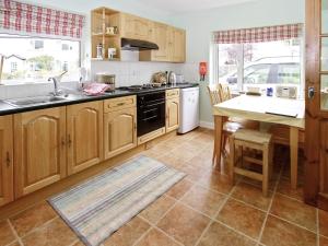 a kitchen with wooden cabinets and a sink and a table at Bridge Cottage in Braithwaite