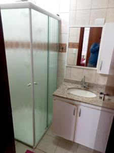 Un baño con ducha, lavabo y espejo. en Apto Pé na Areia com Vista Mar, Churrasqueira e Espaço para 8 Pessoas, en Praia Grande