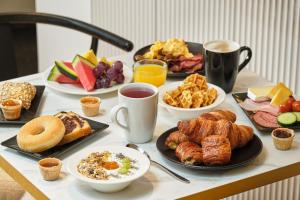 a table topped with plates of breakfast foods and coffee at Hotel Aqua by HappyCulture in Brussels