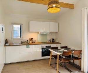 a kitchen with white cabinets and a table and chairs at L'escapade Landaise à 10 minutes des plages in Soustons