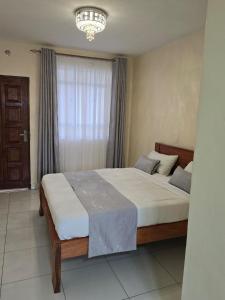 a bedroom with a large bed with a chandelier at SERENSTAY ACCOMMODATIONS Muthwani Kamulu Joska Malaa Nairobi Kangundo road in Juja