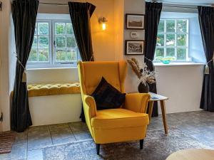 a living room with a yellow chair and a table at Winkle Cottage in Calbourne