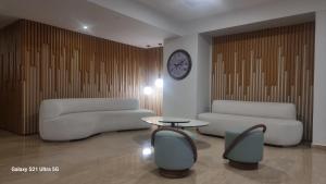 a living room with two couches and a table and a clock at Ponti Beach Hotel in Vasiliki
