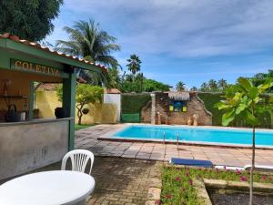 a pool with a table and chairs next to a house at Pousada Dos Cajueiros in Paripueira