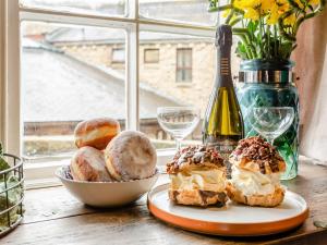 Una mesa con un plato de donas y una botella de vino. en Buttress Retreat, en Hebden Bridge