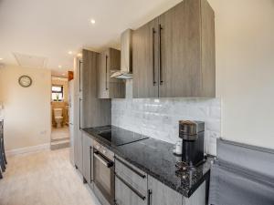 a kitchen with wooden cabinets and a black counter top at Huntspill Cottage in Holbeach