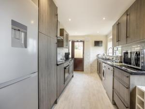 a large kitchen with wooden cabinets and appliances at Huntspill Cottage in Holbeach