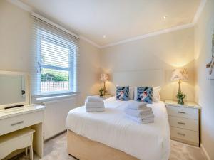 a bedroom with a white bed and a television at Duck Bay Cottage 1 - Uk43934 in Balloch +16 photos