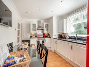 a kitchen with white cabinets and a table with chairs at Duck Bay Cottage 1 - Uk43934 in Balloch