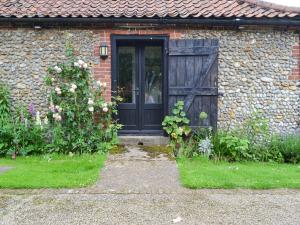 a brick house with a black door and flowers at The Little House in Baconsthorpe