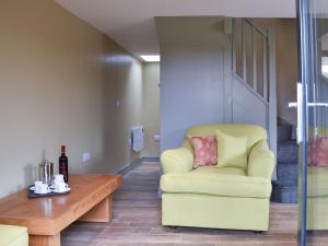 a living room with a yellow chair and a table at The Bothy in Beetham