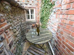 a bottle of wine sitting on a table in a brick wall at Cobble Cottage30C - Ukc2846 in Blakeney